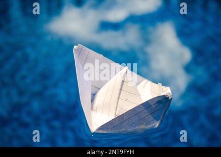 Folded paper boat floating in water Stock Photo