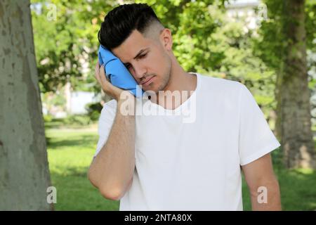 Man with cold pack suffering from heat stroke outdoors Stock Photo