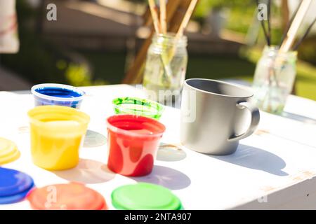 Close up of colorful paints and brushes on table in garden Stock Photo