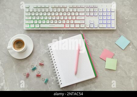 Modern keyboard with RGB lighting and stationery on grey table, flat lay Stock Photo
