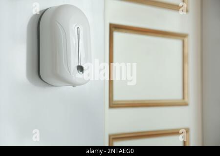 Automatic hand sanitizer dispenser on wall indoors. Space for text Stock Photo
