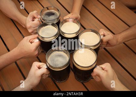 Friends clinking glasses with beer at table, closeup Stock Photo