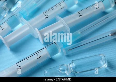 Disposable syringes with needles and ampules on light blue background, above view Stock Photo