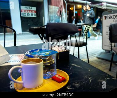 Turkish coffee served with a Ülker chocolate piece and Akdoruk pack of water. Street terrace cafe in Konak. Izmir, Turkey. Stock Photo