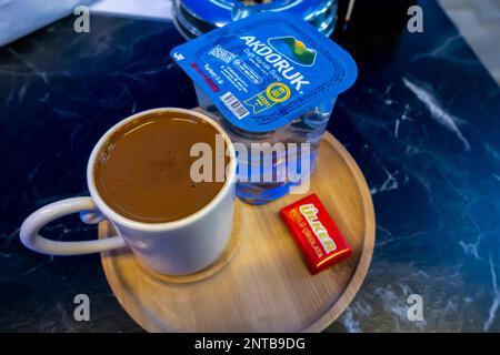 Turkish coffee served with a Ülker chocolate piece and Akdoruk pack of water. Street terrace cafe in Konak. Izmir, Turkey. Stock Photo