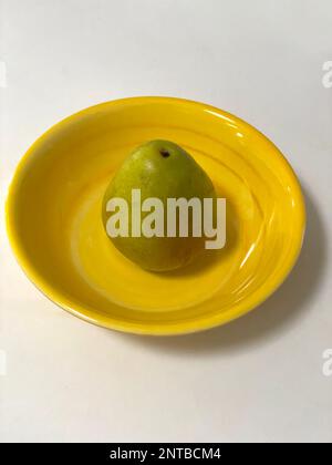 A green pear on a yellow plate. Stock Photo