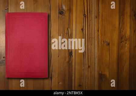 Close-up on a red book on a brown wooden desk. Stock Photo