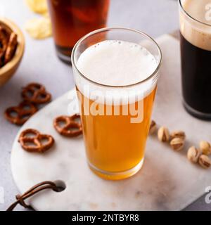 Variety of beer with dark stout, traditional lager and belgian white served with snacks on the table Stock Photo