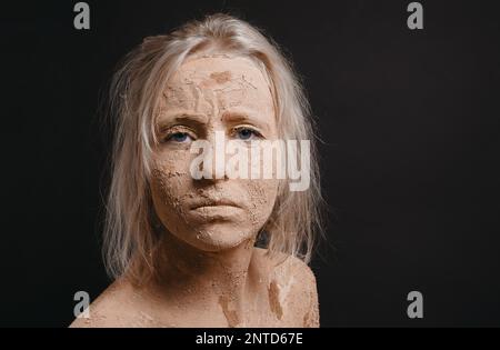 disheveled woman covered in dry cracked mud with copy space Stock Photo