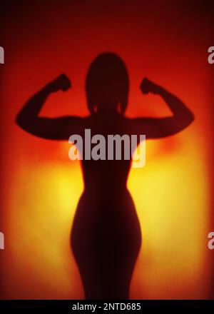 female empowerment or feminism or emancipation concept, silhouette of an anonymous strong woman flexing muscles Stock Photo