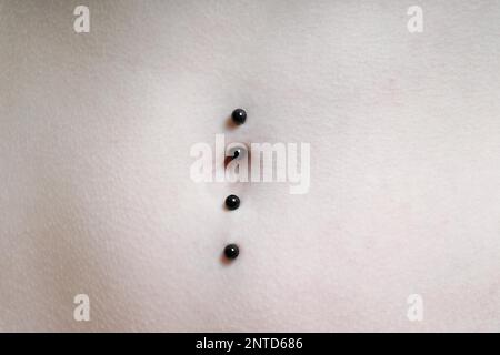 close-up of belly button or navel pierced with double barbell piercing Stock Photo