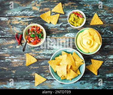 Mexican tortilla chips with guacamole, cheese, salsa dips. Nachos and assorted dips. Mexican party food, appetizers. Top view. Tortilla chips Stock Photo