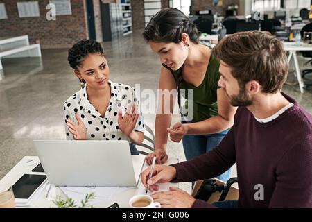 Theyre all part of the planning process. a team of colleagues using a laptop together in a modern office. Stock Photo