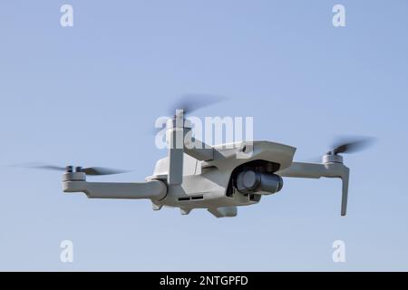 Quadcopter aka drone hangs in the air against the blue sky, copy space Stock Photo