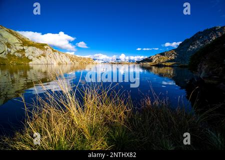 The main range of Brenta Dolomites, partially shrouded in clouds, reflected in the lake Lago Nero. Stock Photo