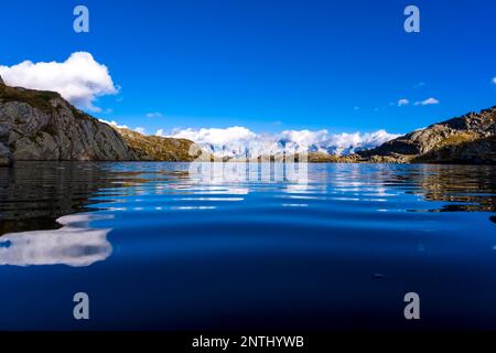 The main range of Brenta Dolomites, partially shrouded in clouds, reflected in the lake Lago Nero. Stock Photo