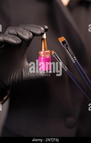 beautician- makeup artist holding paint henna and brushes for eyebrows in a beauty salon, close up. Professional care for face. Natural henna and tool Stock Photo