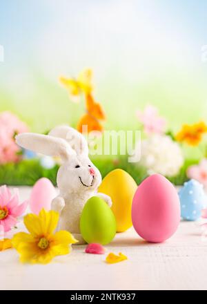 Happy Easter greeting card. Easter eggs, bunny  and spring flowers on table for decoration home for Easter. Stock Photo