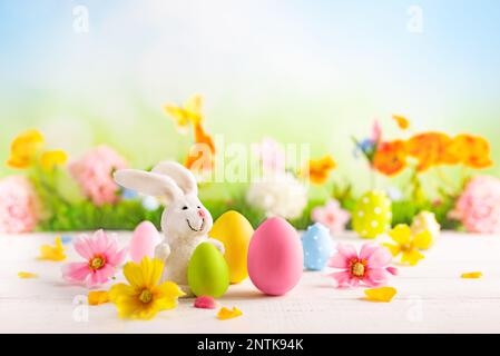 Happy Easter greeting card. Easter eggs, bunny  and spring flowers on table for decoration home for Easter. Stock Photo
