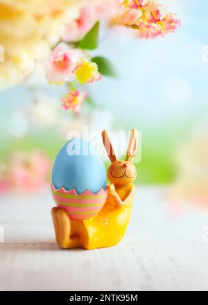 Easter decoration with bunny, Easter eggs and beautiful spring flowers on a blurred light background. Easter concept with copy space. Stock Photo