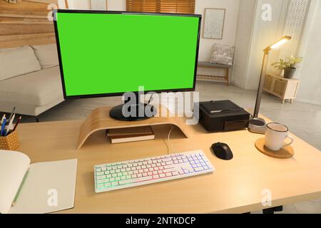 Modern computer and RGB keyboard on wooden table indoors. Mockup green screen Stock Photo