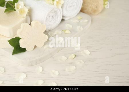 Beautiful jasmine flowers, towels and soap bars on white wooden table Stock Photo