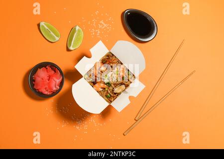 Noodle wok served on orange background, flat lay Stock Photo