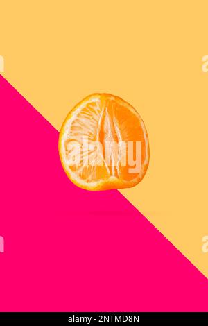Peeled mandarin or clementine isolated on soft peach color background Stock Photo