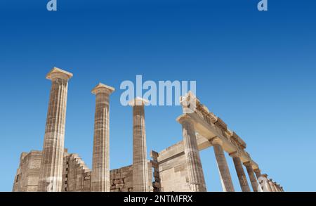 Ancient Greek antique temple facade stone ruins and columns against blue sky Stock Photo
