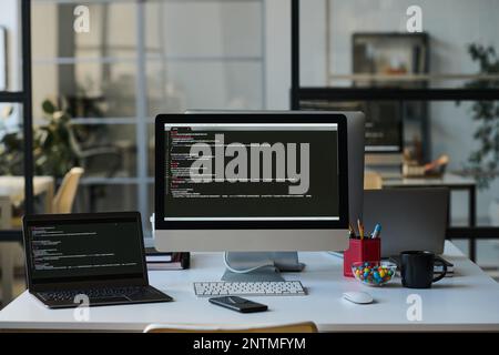 Workplace of developer with computers with programming codes on the screens on table Stock Photo