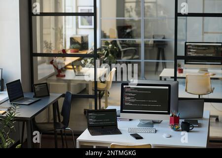 Horizontal image of modern IT office with workplaces of programmers with computers on desks Stock Photo
