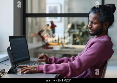 Young serious programmer working online with gadgets at his workplace, he typing codes for program Stock Photo
