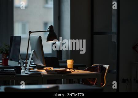 Horizontal image of workplace of programmer with computer on table in dark office Stock Photo