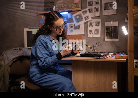 Young woman fixing laptop. Disassembling a notebook and cleaning its cooling system. Dust and dirt on computer fan. Computer technician working in ret Stock Photo
