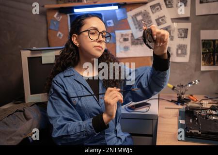 Female repairman fixing broken laptop in retro repair shop or garage. Fixing laptop. Disassembling a notebook and cleaning its cooling system. Occupat Stock Photo