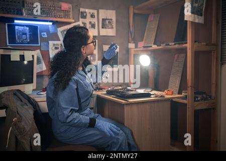 Repairman disassembling laptop motherboard, looking on damaged memory board. Engineer fixing broken computer at work in retro repair shop. Electronic Stock Photo