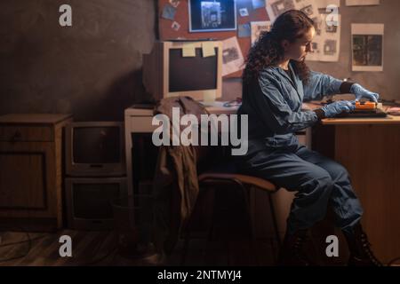 Electronic renovation in old retro repair shop. Women repairman tinkering computer component using multimeter. Copy space Stock Photo