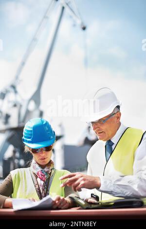 This copyspace will help promote your business. Two dock workers holding paperwork while standing in the shipyard. Stock Photo