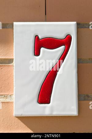 House number 7 over brick sunny wall. Houses with personality concept Stock Photo