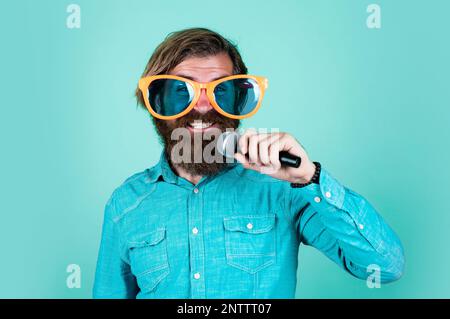 Music is only love looking for words. performer having fun. mature bearded man in funny party glasses sing song. brutal male hipster with microphone. Stock Photo
