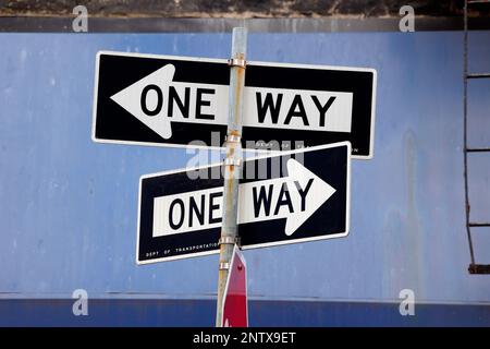 Opposing One Way traffic signs against a blue background Stock Photo