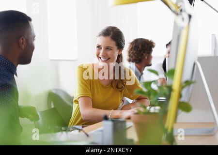 Sharing a work laugh. Shot of a team of designers talking while working on their computers. Stock Photo
