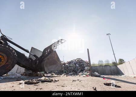 Yellow wheel loader, with lifted scrap grapple, moving along the ...