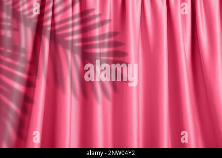 Magenta background of the plush curtain with the shadow of palm leaves over it, spring and summer concept Stock Photo