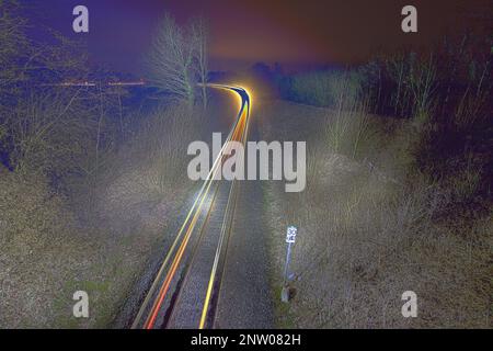 Long-term HDR shot at night of train tracks where a train has passed and thus left light traces. Stock Photo