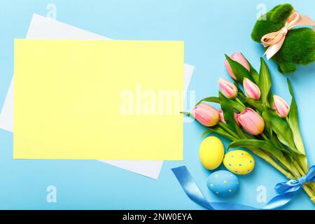 Easter card. Bouquet of tulips bunny eggs on a blue background. Empty sheet of paper with space for text and copy space Stock Photo