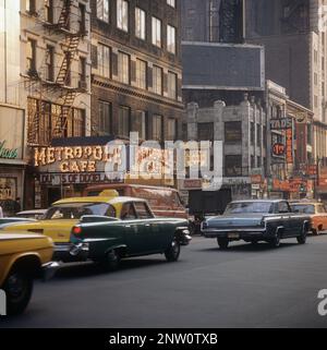 USA New York 1964. A street scene with cars and taxis driving on Broadway in the area of  Times Square on Manhattan. Metropole cafe with it's lit signs is in focus.  Credit Roland Palm ref 5-38-11 Stock Photo