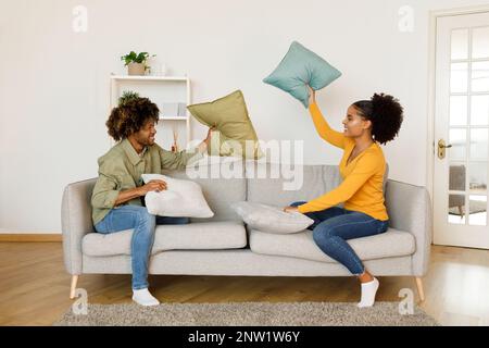 Joyful Black Couple Having Pillow Fight For Fun At Home Stock Photo