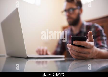 Using all the latest tech. Shot of a handsome young hipster working on a laptop. Stock Photo