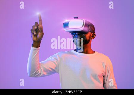 Black man in VR headset touching something invisible Stock Photo